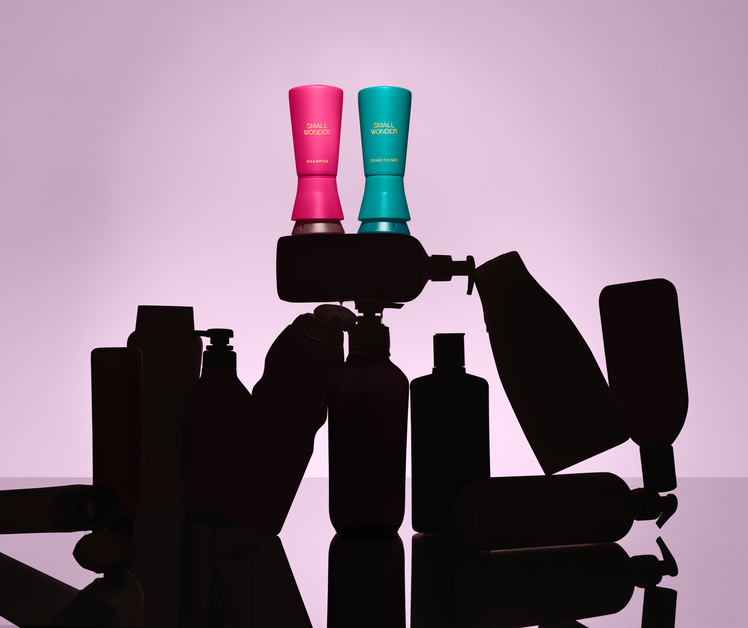 Two bottles, a Small Wonder Shampoo and Conditioner, atop silhouettes of nondescript other products