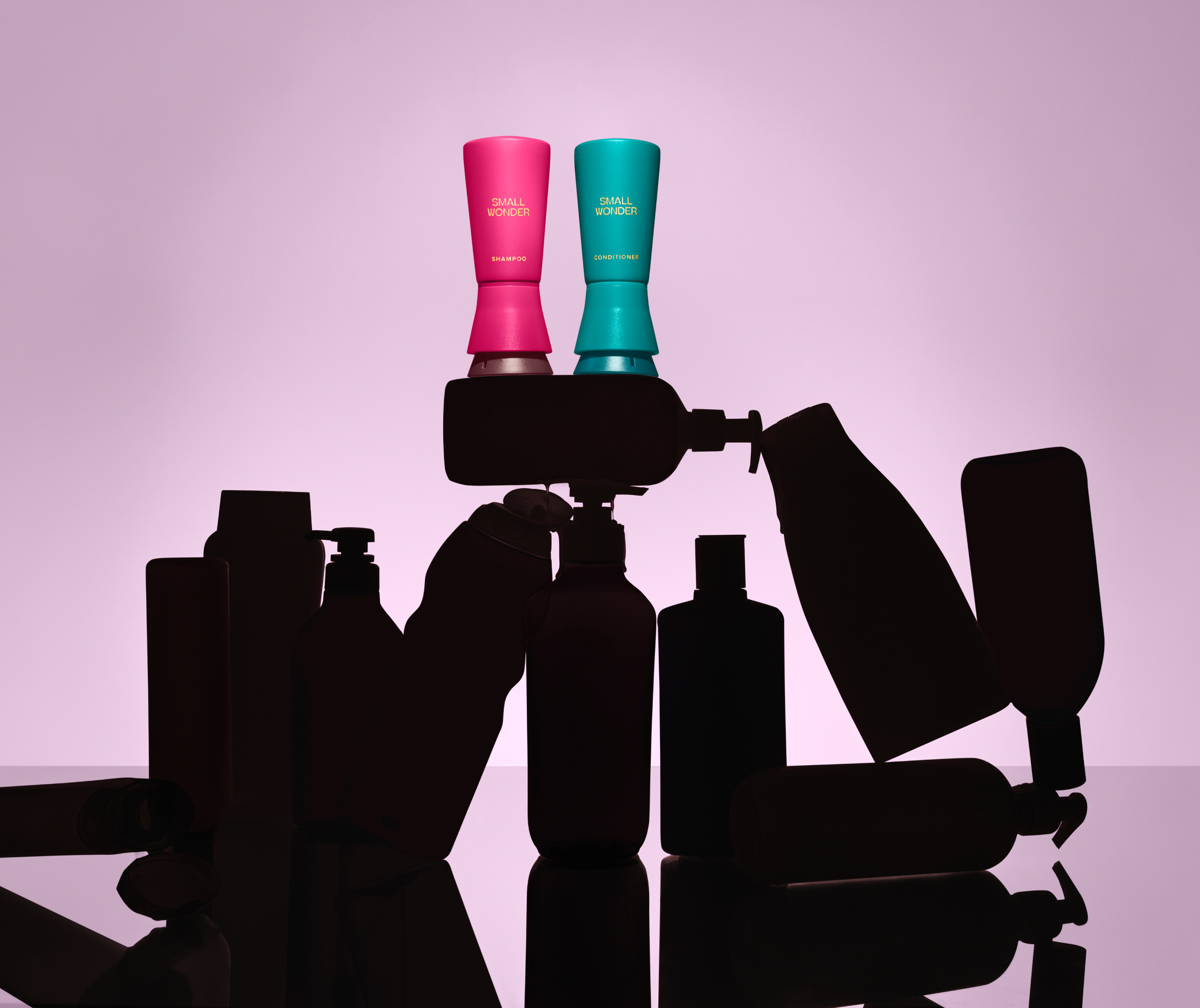 Two bottles, a Small Wonder Shampoo and Conditioner, atop silhouettes of nondescript other products