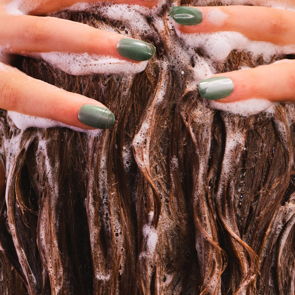 Woman with green nails lathering hair
