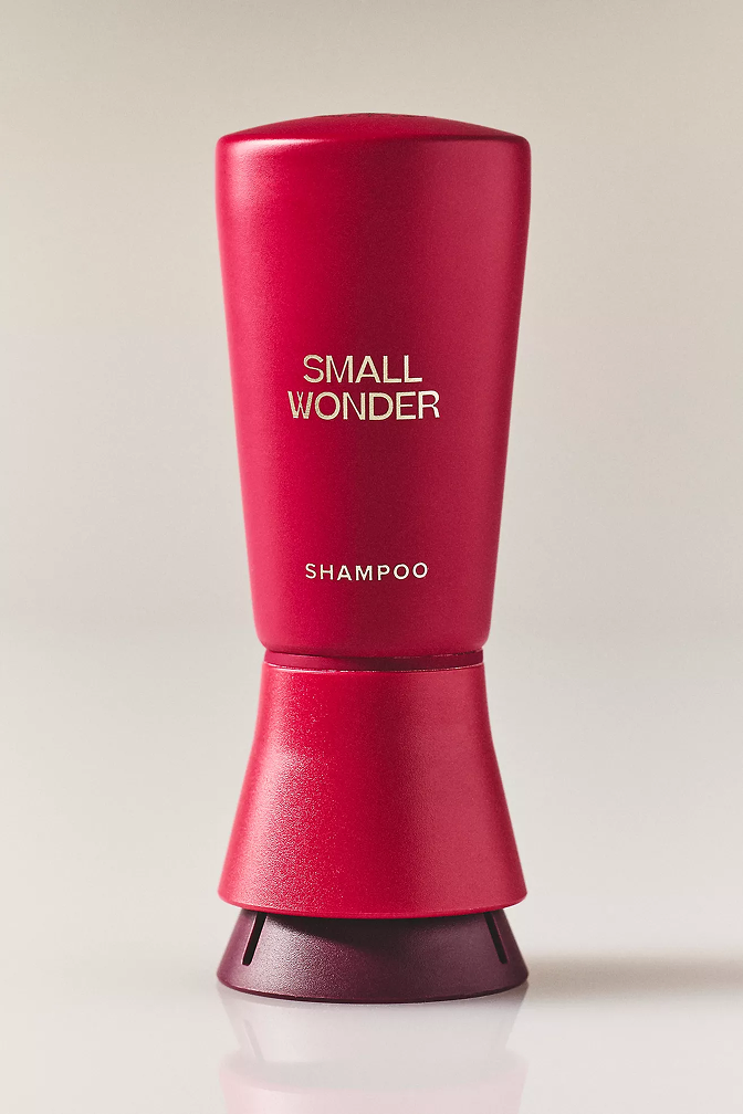 Red shampoo bottle labeled 'Small Wonder' on a light background