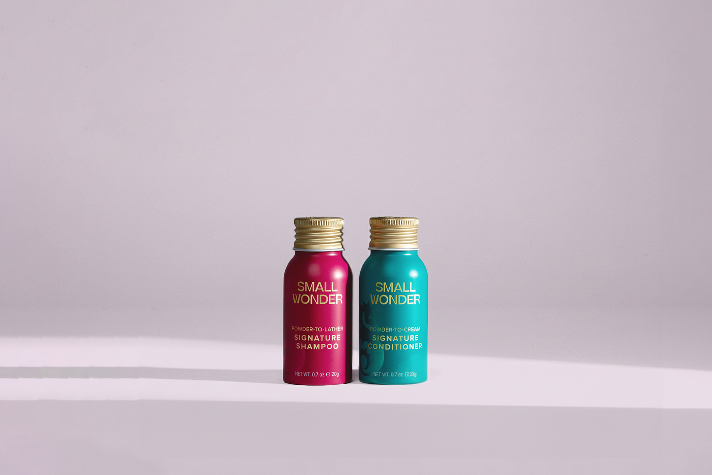 Two bottles of 'Small Wonders' signature shampoo and conditioner on a light purple background.