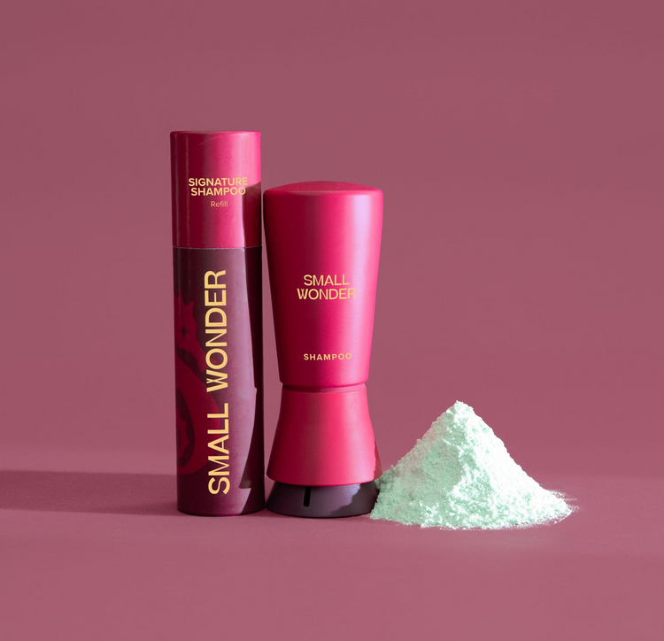 Small Wonder Red Shampoo Bottle and Refill tube next to a pile of green powder