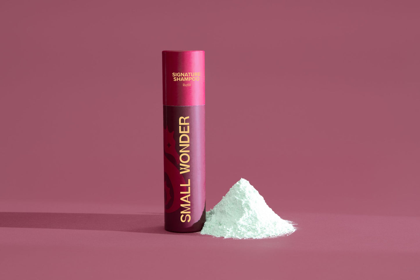 Red cylindrical container labeled 'Small Wonder Shampoo' on a red background & white powder