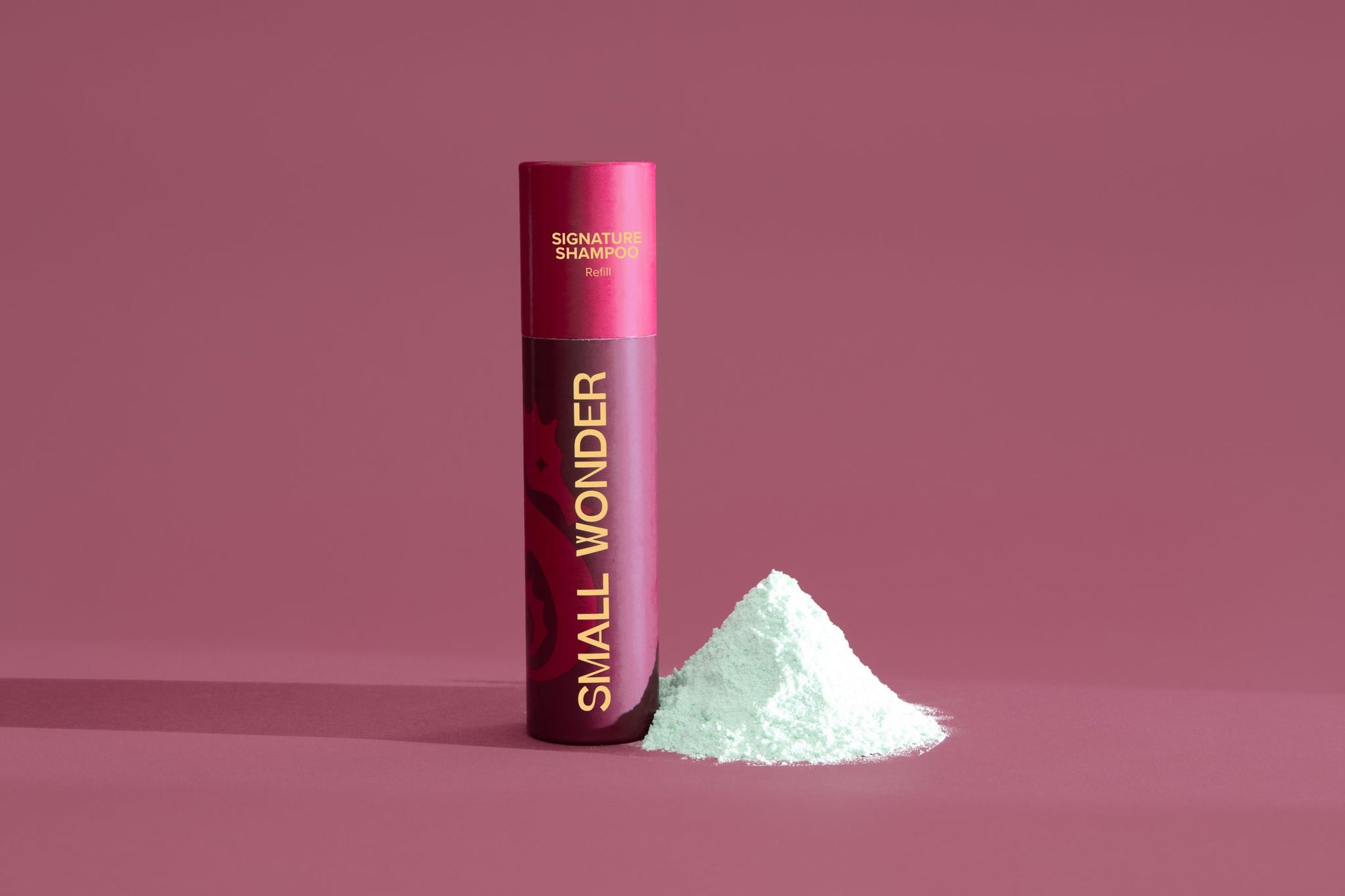 Red cylindrical container labeled 'Small Wonder Shampoo' on a red background & white powder