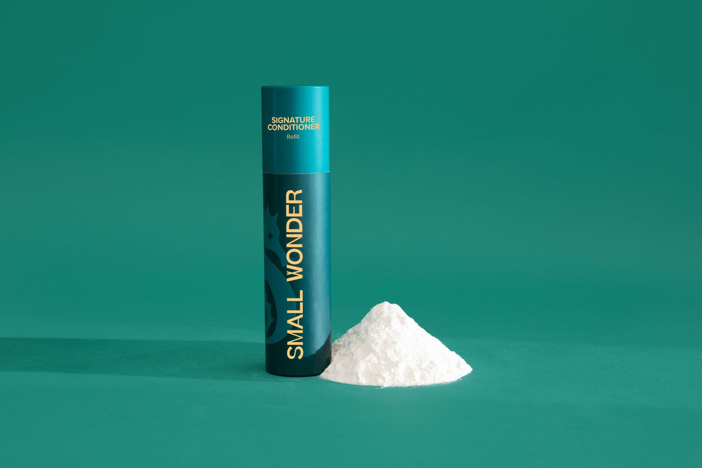 Teal cylindrical container labeled 'Small Wonder Conditioner' on a green background & white powder
