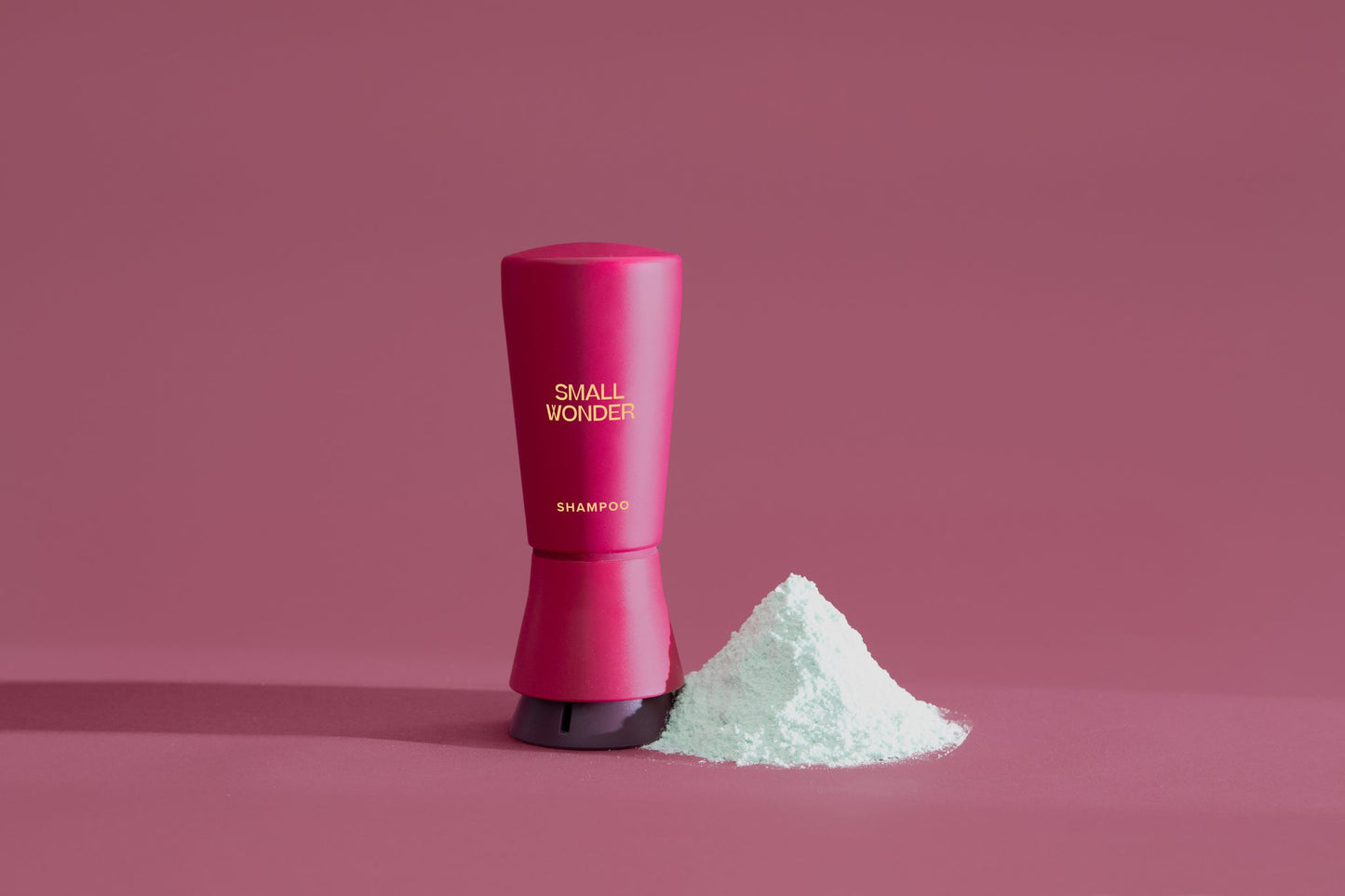 Red cylindrical container labeled 'Small Wonder Shampoo' on a red background & white powder